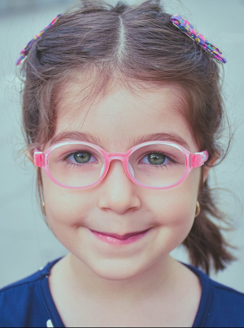 girl in blue and white shirt wearing pink framed eyeglasses